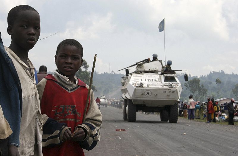 Children watch as U.N. peacekeepers in armoured personnel carriers (APC) patrol a key road linking Goma and Rutshuru in eastern Congo