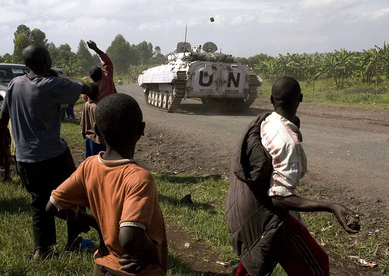 People throw stones at UN peacekeepers patrolling on a road in Kibati