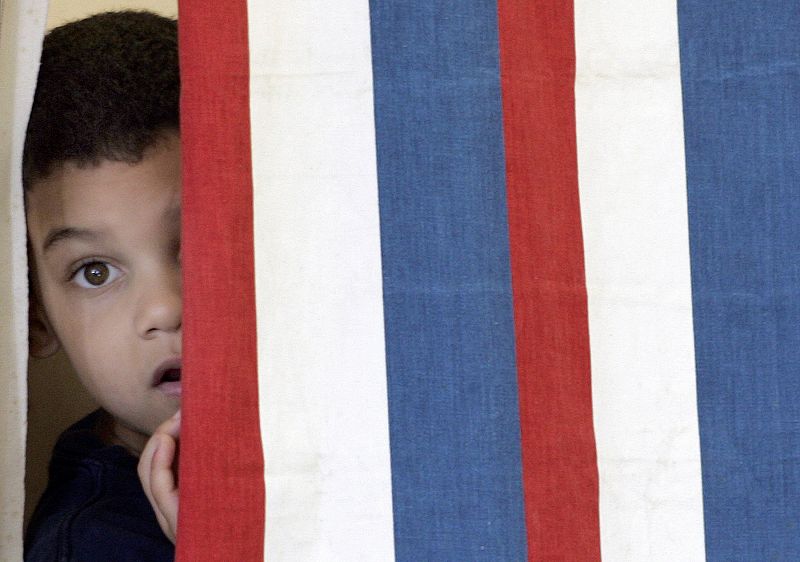 Un niño se asoma en una cabina de voto en New Hampshire.