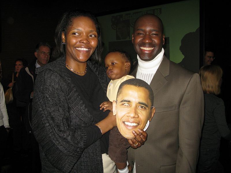 Una familia afroamericana posa con su hija y la careta de Barack Obama.