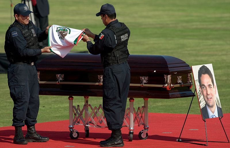 Federal policemen fold the Mexican flag front the coffin of Interior Minister Mourino during a ceremony in Mexico City