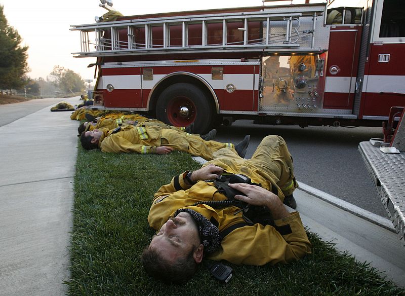 Los bomberos se toman un descanso en su lucha contra el fuego en Carbon Canyon, California