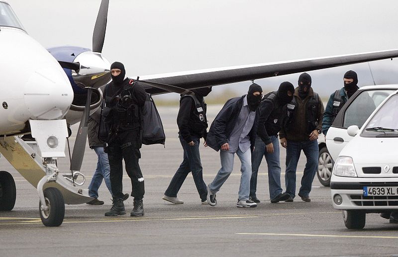 Hooded police walk near the plane with on board suspected Basque separatist rebel group ETA military chief Garikoitz Aspiazu Rubina at the Biarritz' airport