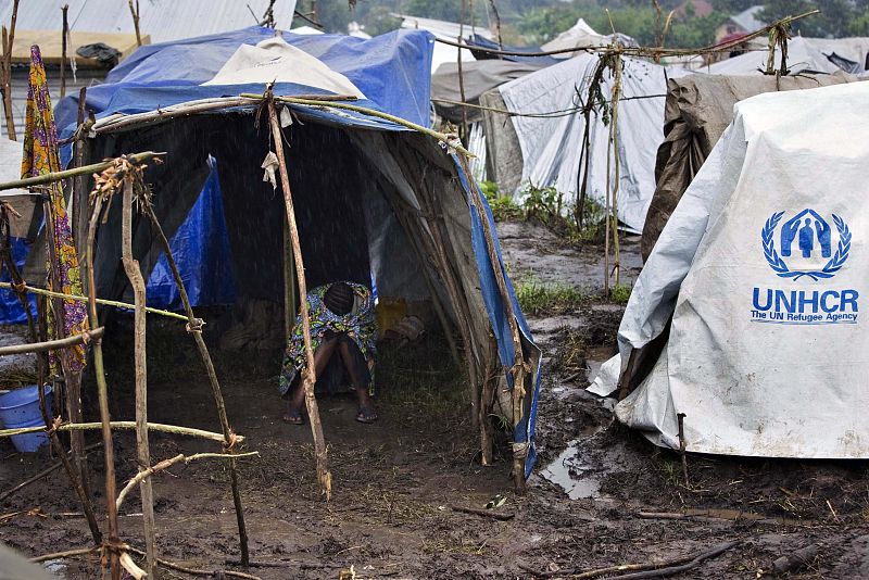 Woman displaced by fighting takes shelter from the rain in a makeshift tent in Kiwanja