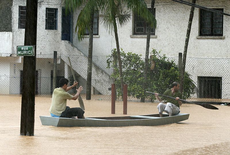 Men paddle a boat on a flooded street in Blumenau city in the Brazilian state of Santa Catarina