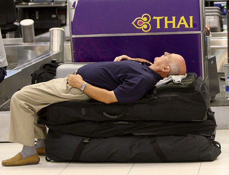 Un pasajero duerme sobre su equipaje del aeropuerto internacional de Bangkok.