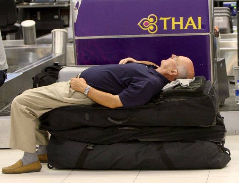  Un pasajero duerme sobre su equipaje del aeropuerto internacional de Bangkok.