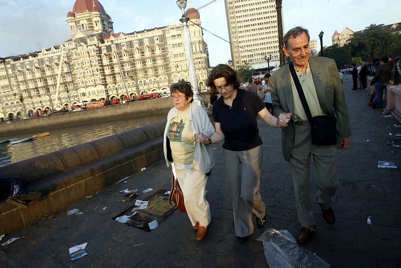 An employee of the Taj Hotel (seen in the background) comforts foreign guests in Mumbai