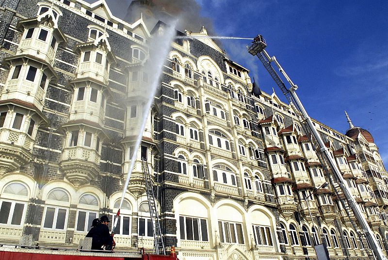 Un grupo de bomberos tratan de apagar el fuego que afecta al hotel Taj