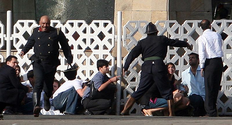 Un grupo de gente intenta protegerse de los disparos que reciben desde el hotel Taj