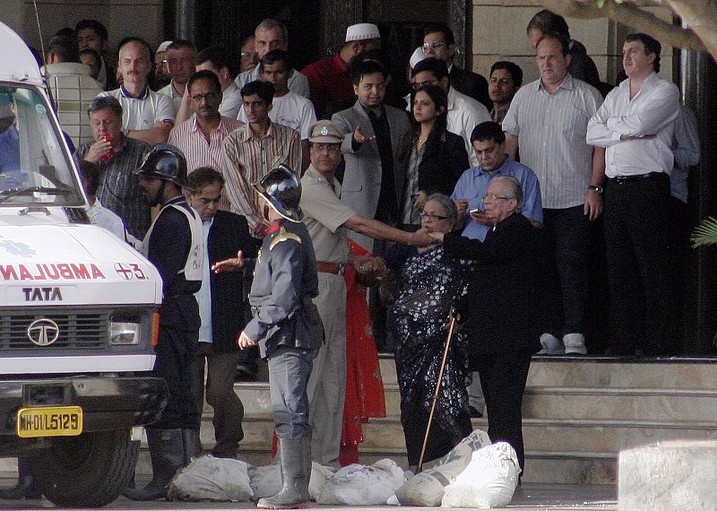 Guests stranded inside Taj Mahal Hotel stand at the entrance while waiting to be brought out of the hotel in Mumbai