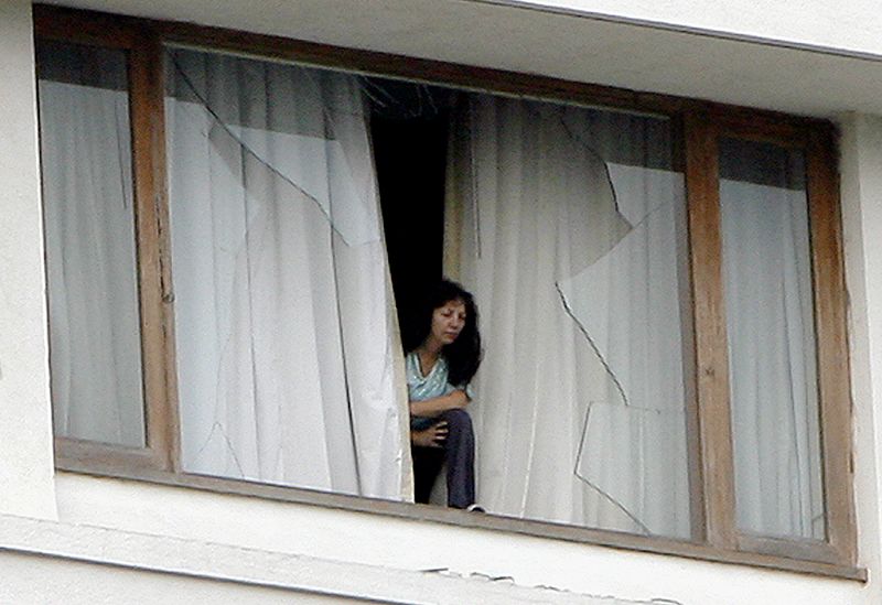 A hotel guest looks out from a broken window of the besieged Trident-Oberoi Hotel in in Mumbai