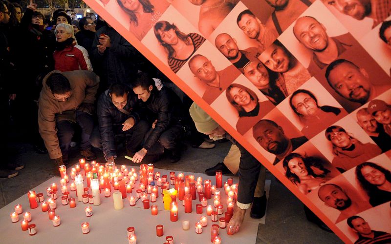 Varias personas colocan velas en el acto organizado por el Colectivo de Lesbianas, Gays, Transexuales y Bisexuales de Madrid (COGAM).