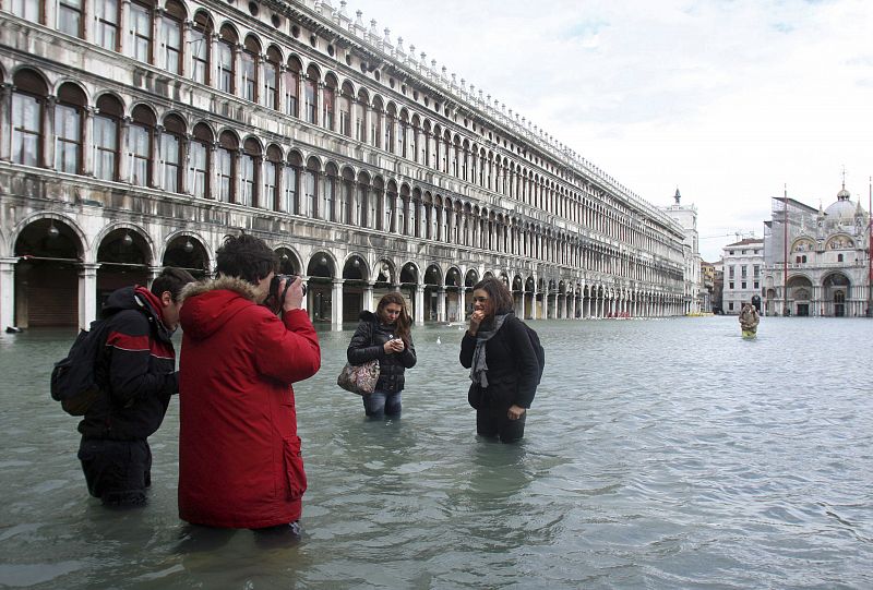 Los turistas toman fotos de la plaza de San Marcos inundada