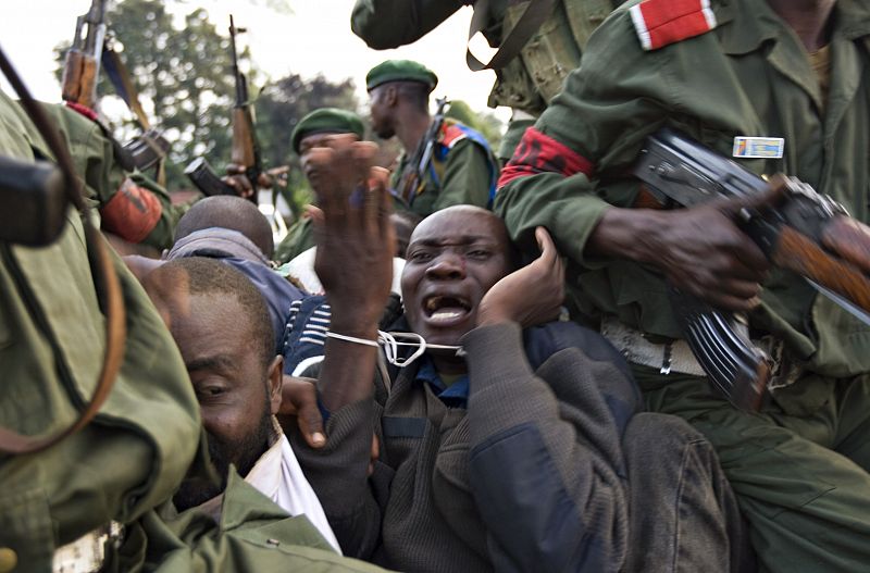 A prisoner with bound wrists pleads while being beaten by government soldiers in eastern Congo