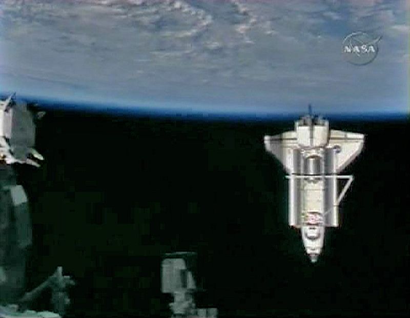 El transbordador espacial Endeavour visto con la tierra en el fondo y parte de la Estación Espacial Internacional