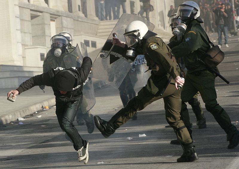 A protester tries to escape from riot policemen during a demonstration in Athens