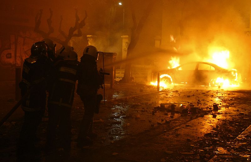 Unos bomberos intentan apagar un coche ardiendo en la Universidad Politécnica de Atenas