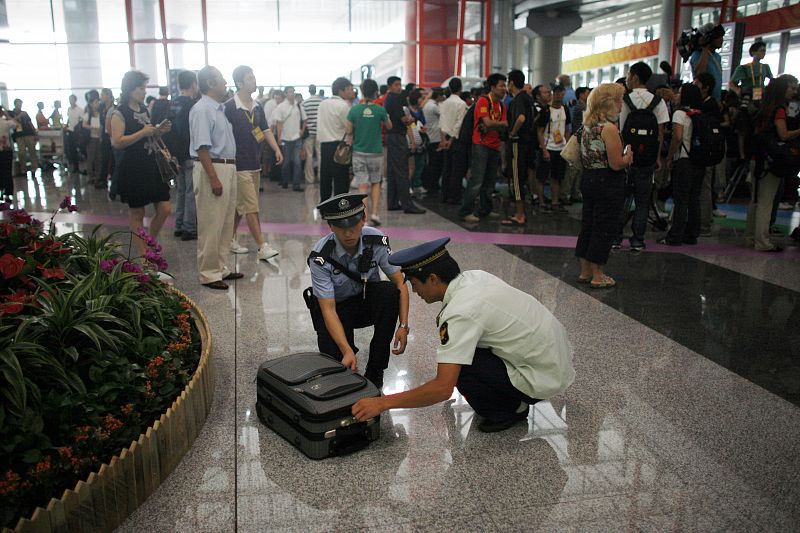 Dos agentes de policía abren una maleta abandonada en la terminal 3 del aeropuerto de Pekín