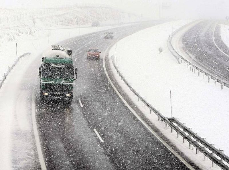 Varios vehiculos circulan por la autovía A-67 a la altura del puerto de El Pozazal en medio de una de las intensas nevadas que están cayendo en las zonas interiores de la cornisa cantábrica. 