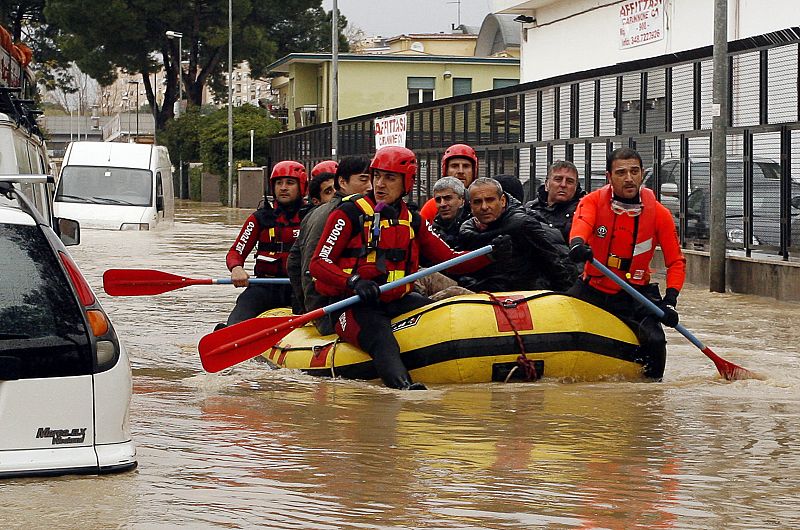 Fire department rescuers ferry stranded people through flood waters near Via Tiburtina in Rome