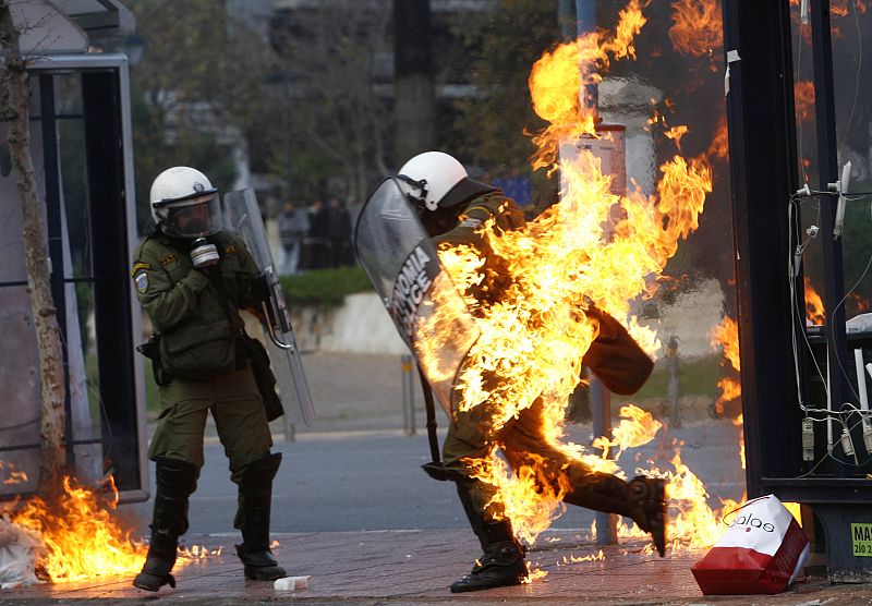 Un policía griego ha sido alcanzado por un artefacto incendiario en medio de las protestas violentas que se están produciendo en Atenas el 12 de diciembre de 2008.