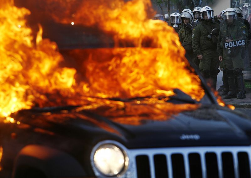 Arde un coche en una calle de Atenas, Grecia, durante los disturbios que desde hace una semana se producen en la capital del país y en otras ciudades.