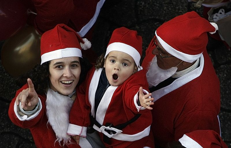 A mother with her daughter dressed as Santa Claus attend a parade in Porto