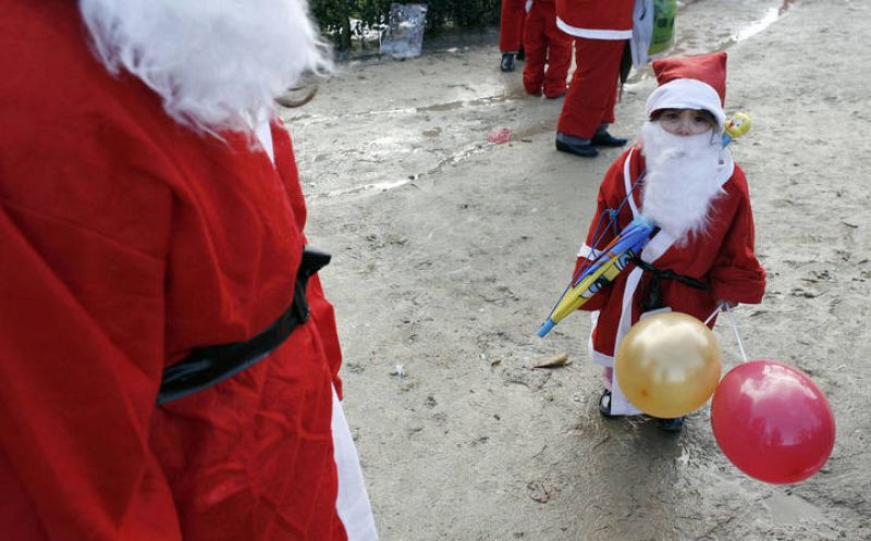 A child dressed as Santa Claus stands during a parade in the streets of Porto