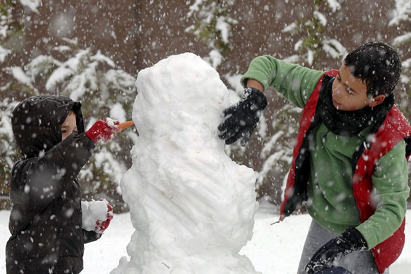 Dos niños realizan un muñeco de nieve en Viana de Cega, en Valladolid