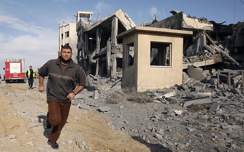 A Palestinian man runs beside a destroyed Hamas police compounds after an Israeli air strike in Gaza