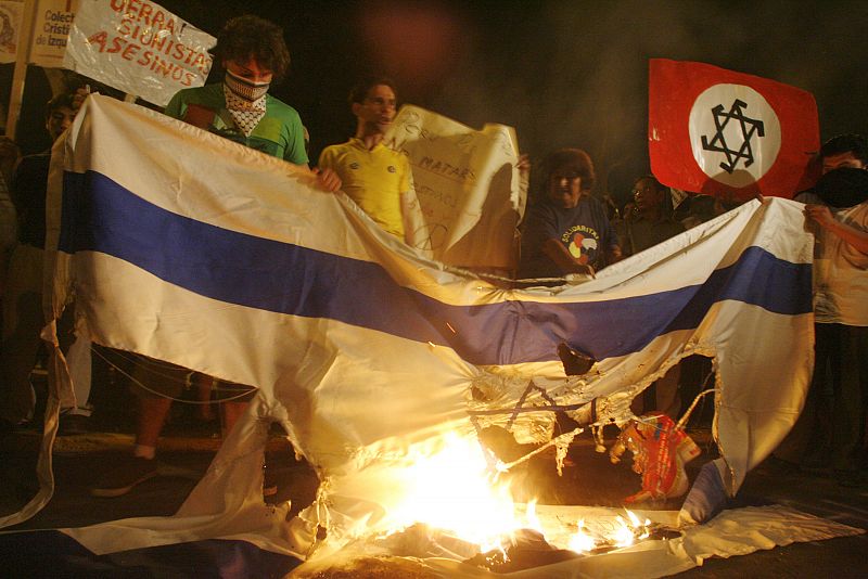 Protesters burn an Israeli flag during demonstrations against the bombing of the Gaza Strip outside Israel's embassy in Lima