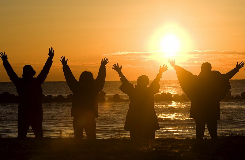 Un grupo de japoneses eleva sus brazos al sol el 1 de enero de 2009, como un acto de celebración al primer amanecer del año en las playas de Misaki, provincia de Chiba (Japón).