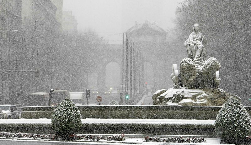 La estatua de la Cibeles con la Puerta de Alcalá al fondo durante la intensa nevada que cae hoy sobre la ciudad de Madrid y sus alrededores.