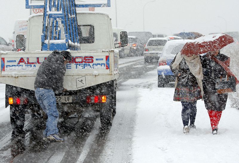 Un hombre trata de empujar su vehículo, parado a causa de la nieve en la M-40 de Madrid.