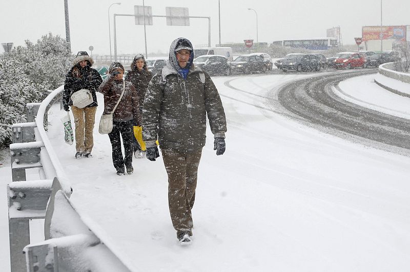 Usuarios de autobuses detenidos a causa de la nieve tratan de alcanzar una estación de metro junto a la M-40 de Madrid.