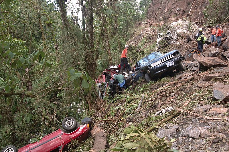 Members of the Red Cross look for survivors near damaged cars after an earthquake in Cinchona of Vara Blanca