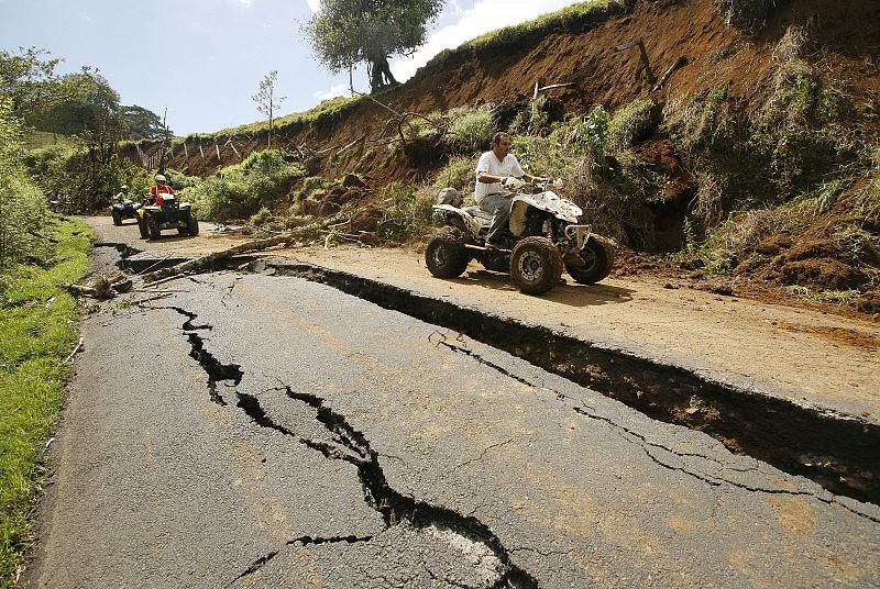 People ride past a crack in the road after a 6.1-magnitude earthquake in Sinchona of Vara Blanca