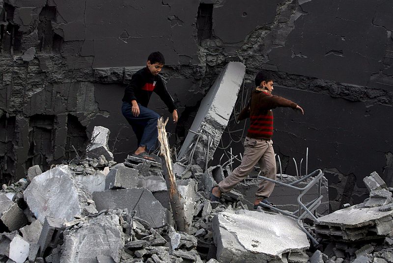 Dos niños caminan sobre los escombros de un edificio destruido en un ataque aéreo israelí en el campo de refugiados de Shati, en la Franja de Gaza.