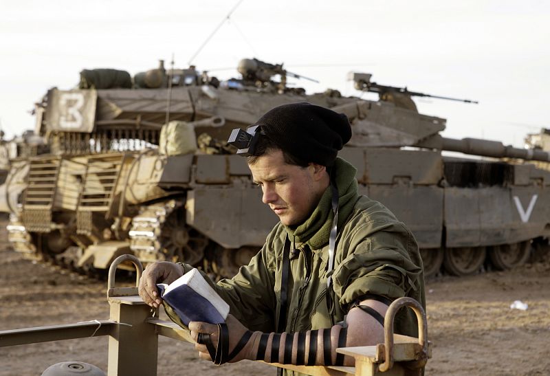Un soldado israelí reza junto a los tanques en el norte de la Franja de Gaza.