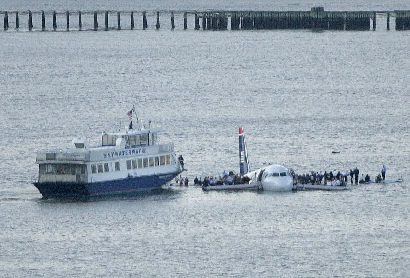 Passengers stand on the wings of a U.S. Airways plane as a ferry pulls up to it after it landed in the Hudson River in New York