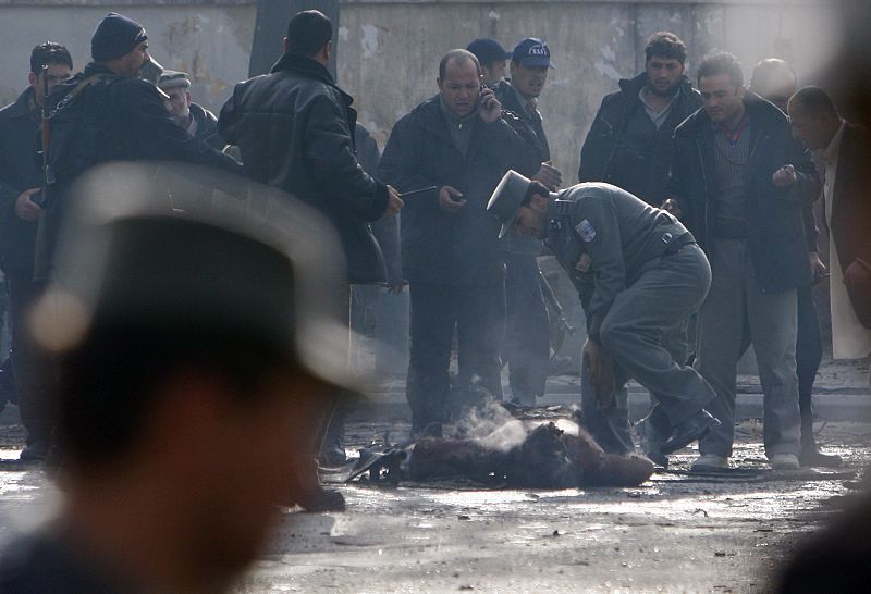 A policeman tries to get hold of the remains of a victim after a blast at the German embassy in Kabul