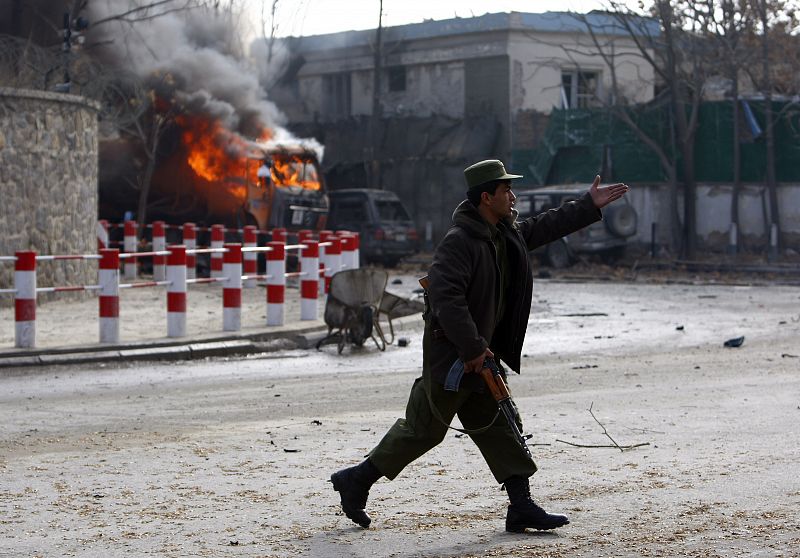 Afghan policeman reacts in front of a blast outside the German embassy in Kabul