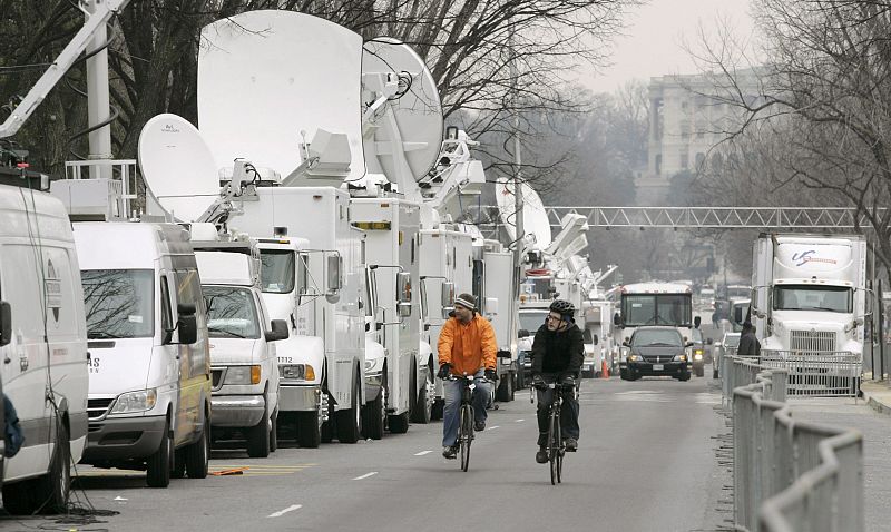 Ciclistas pasan junto a una línea de camiones de televisión satelital, durante los preparativos para la toma de posesión del que se convertirá en el presidente número 44 de EE.UU, el presidente electo Barack Obama, en Washington.