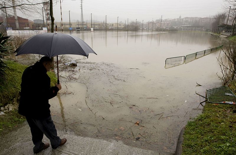 Un hombre observa un campo de rugby totalmente anegado por el agua en Hernani.