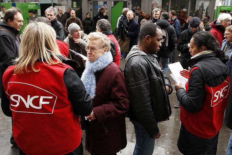 Commuters speak with employees of French SNCF railways in front of the closed entrance of the Gare Saint Lazare train station in Paris