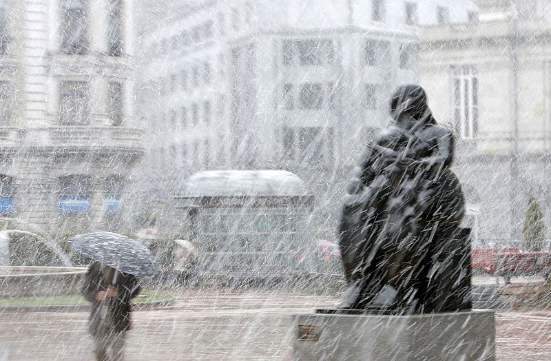 Un hombre se protege de la nieve que cae en Oviedo, Asturias.