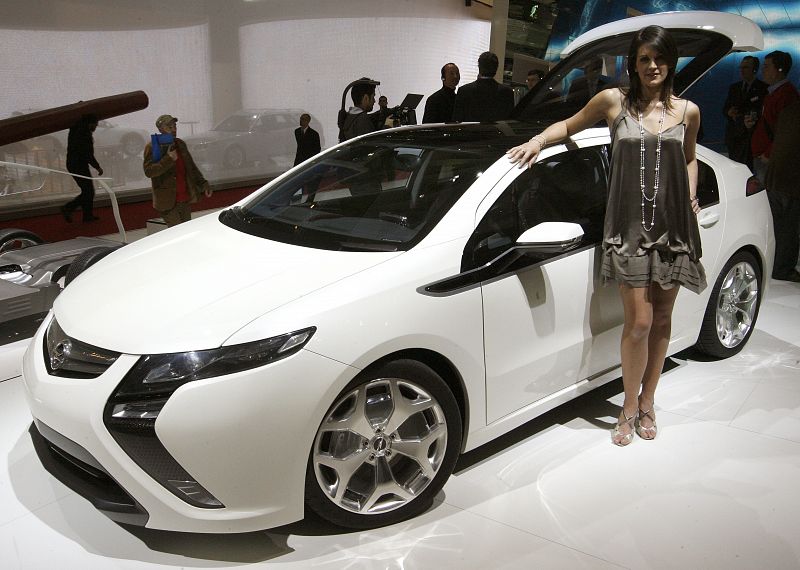 A model poses beside a battery-powered Opel Ampera car at the exhibition stand of General Motors Corp's German unit Opel during a preview day of the 79th Geneva Car Show at the Palexpo