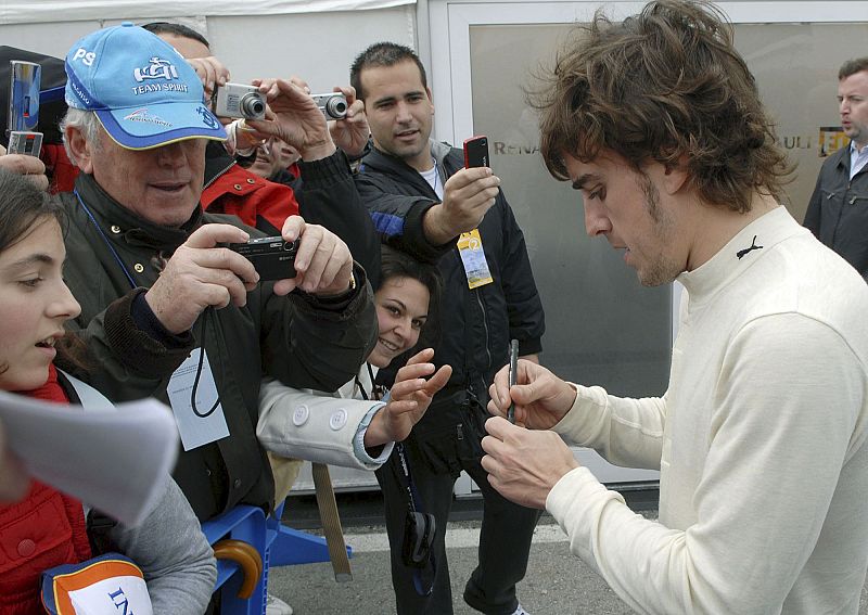 Alonso firma autógrafos a un grupo de aficionados durante los entrenamientos de pretemporada de Fórmula Uno.