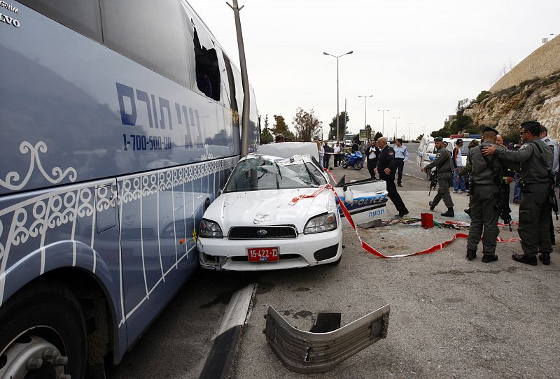 Autobús y coche de policía israelí contra los que ha chocado la excavadora